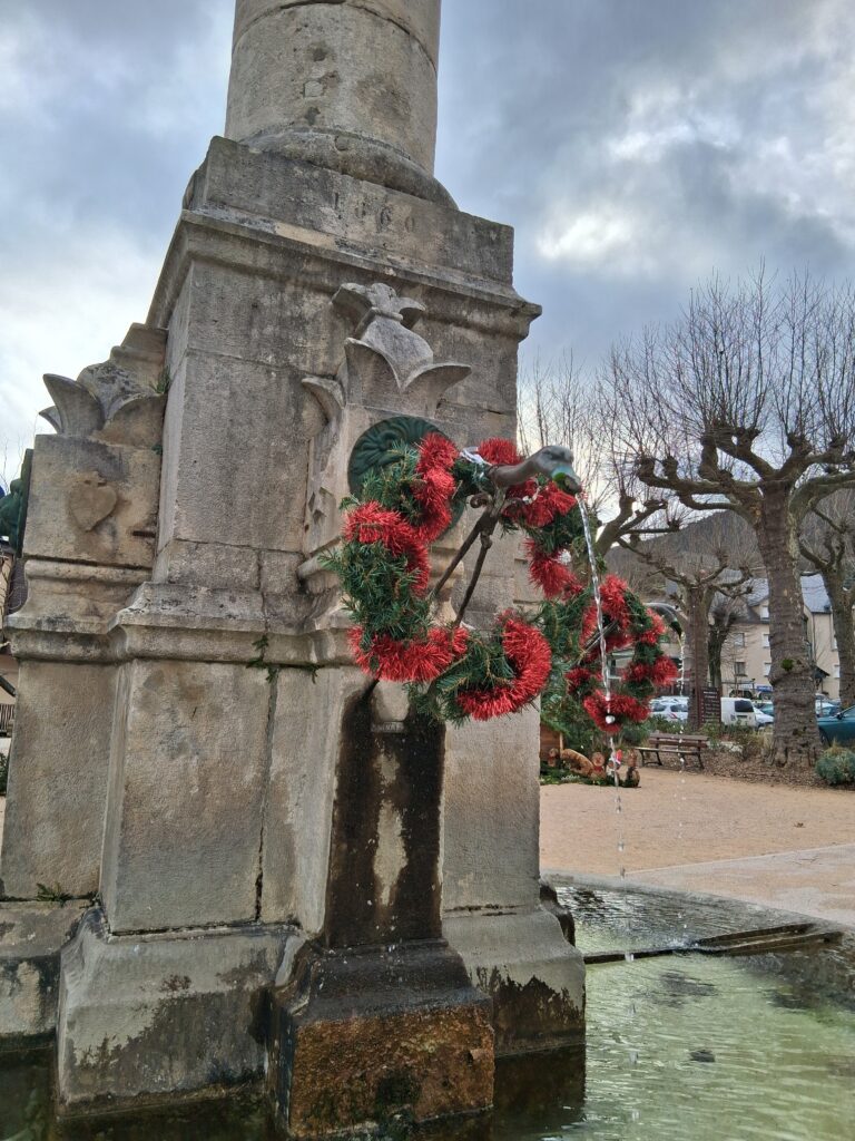 La fontaine de la place décorée avec des couronnes de Noël vertes et rouges